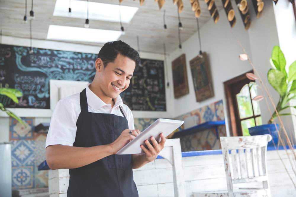 man smiling while holding a tablet