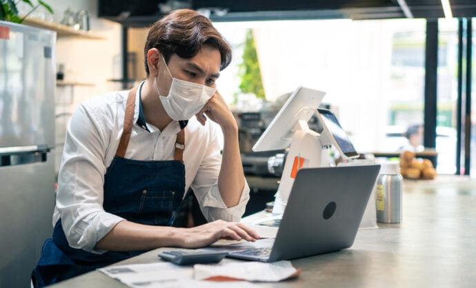 Business owner looking at laptop, feeling sad about another rejected business loan application