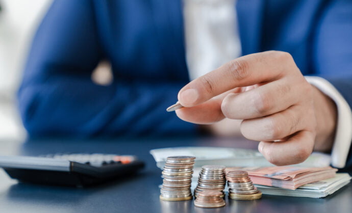 Businessman,Holding,Euro,Cents,Coins,Dollar,Bills,On,Table,With