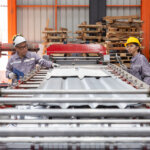 Engineers Overseeing Metal Sheet Production in Factory